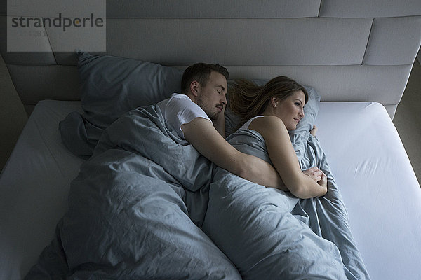 Draufsicht des im Bett liegenden Paares zu Hause