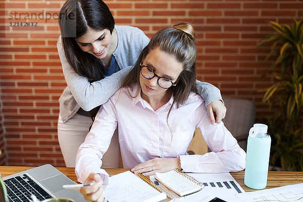 Zwei Geschäftsfrauen mit Notebook am Schreibtisch im Büro