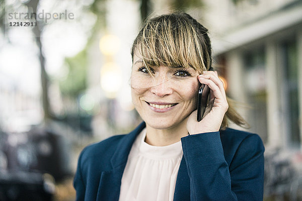 Porträt der lächelnden Geschäftsfrau auf dem Handy im Freien