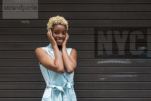 USA  New York  glückliche junge blonde Afroamerikanerin  lächelnd  Hand auf Kopf