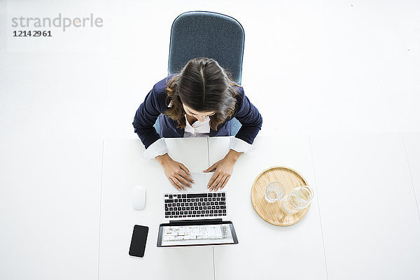 Geschäftsfrau sitzt am Schreibtisch im Büro und arbeitet am Laptop  Draufsicht