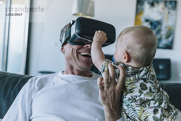 Glücklicher Mann mit Baby mit VR-Brille