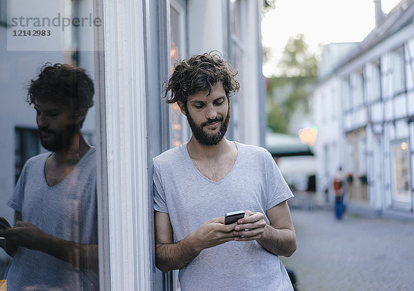 Mann schaut auf Handy in der Stadt