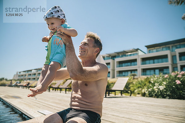 Glücklicher Vater und kleiner Sohn am Pool während der Sommerferien