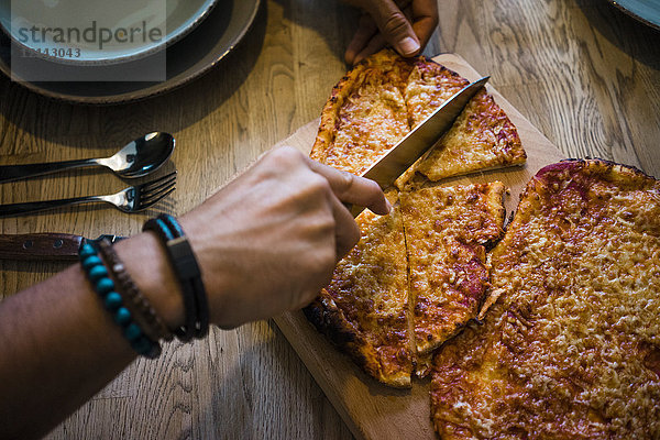 Knusprige hausgemachte Pizza mit dem Messer von Hand schneiden