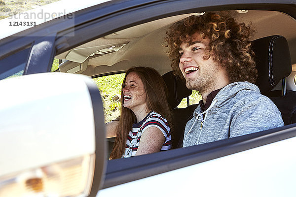 Lachende junge Frau mit Freund beim Autofahren