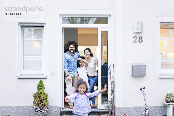 Lachende Familie wartet am Eingang ihres Hauses