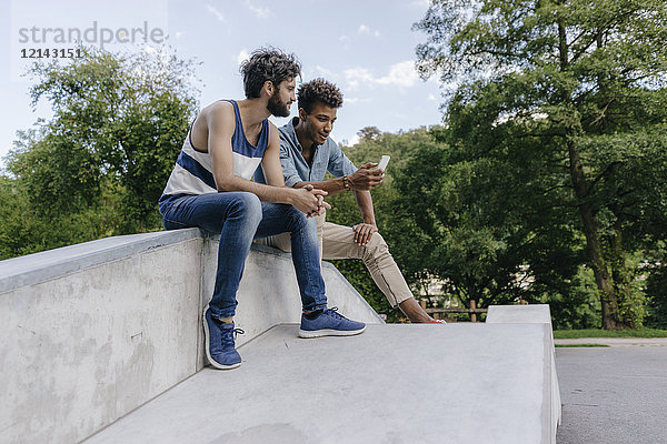 Zwei Freunde teilen sich das Handy im Skatepark