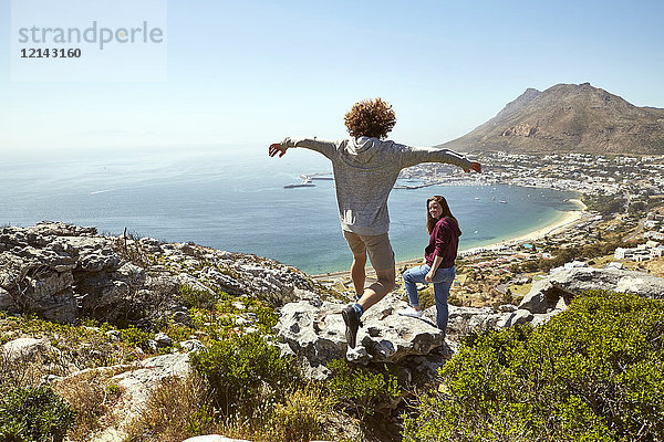 Südafrika  Kapstadt  junges Paar auf einer Reise an der Küste mit einem Mann beim Springen