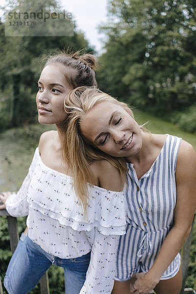 Lächelnde junge Frau ruht auf der Schulter der Freundin