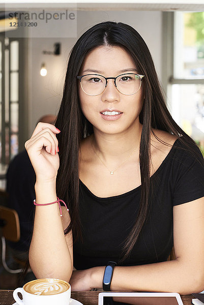 Porträt einer asiatischen jungen Frau beim Blick auf die Kamera in einem Coffee-Shop