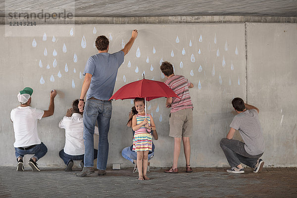 Menschen malen Regentropfen auf Betonwand  kleines Mädchen steht mit rotem Regenschirm