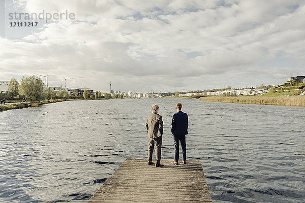 Zwei Geschäftsleute stehen auf einem Steg am See