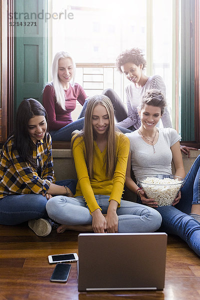 Gruppe von Freundinnen  die gemeinsam zu Hause auf den Laptop schauen