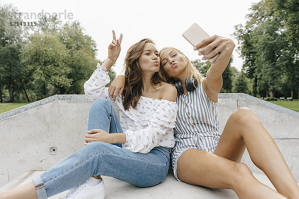 Zwei glückliche junge Frauen  die einen Selfie in einem Skatepark nehmen.