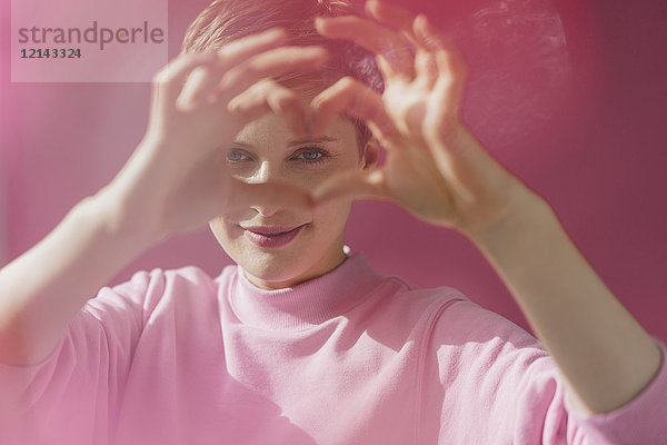 Porträt einer Frau in rosafarbenem Herzen mit ihren Händen