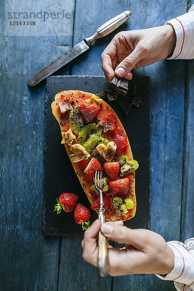 Nahaufnahme von Frauenhänden beim Essen von Papaya mit Kiwi  Banane und Erdbeeren