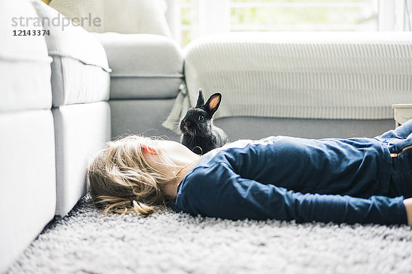 Mädchen mit Hase im Wohnzimmer liegend
