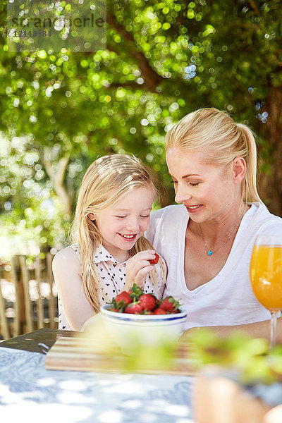 Mädchen mit Mutter beim Essen von Erdbeeren
