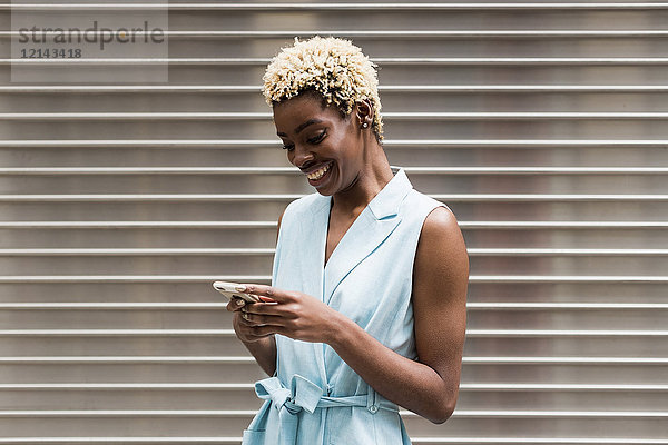 USA  New York  junge blonde Afroamerikanerin mit Smartphone  lächelnd