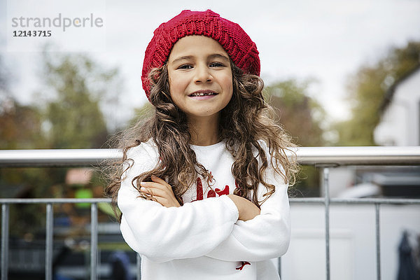 Porträt eines lächelnden Mädchens mit Zahnlücke und rotem Wollhut