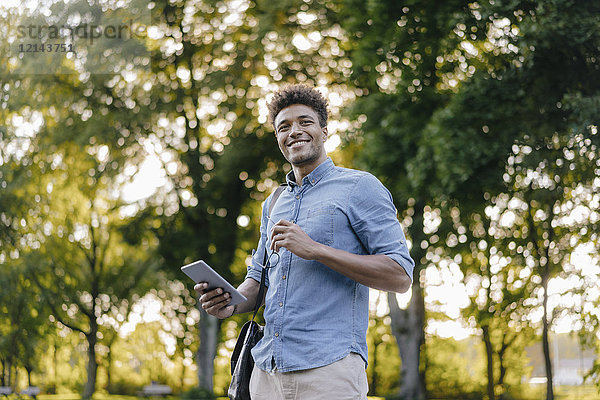 Lächelnder junger Mann mit Handy im Park