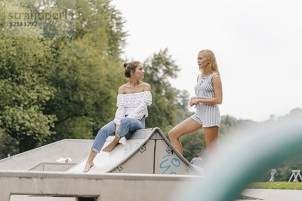 Zwei junge Frauen  die in einem Skatepark reden.