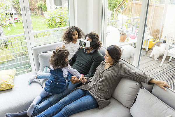 Glückliche Familie sitzend auf der Couch  Vater mit VR-Brille