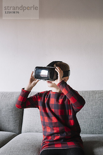 Mädchen sitzt auf der Couch im Wohnzimmer mit Virtual Reality Brille