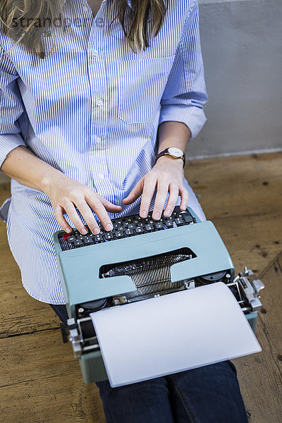 Nahaufnahme der auf dem Boden sitzenden Frau mit der Schreibmaschine
