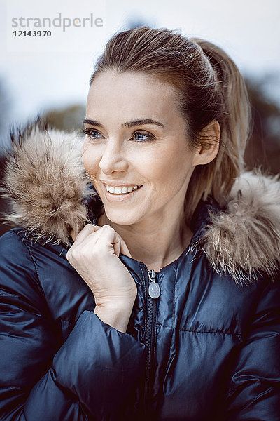 Porträt einer lächelnden Frau in Winterjacke mit Fellkragen
