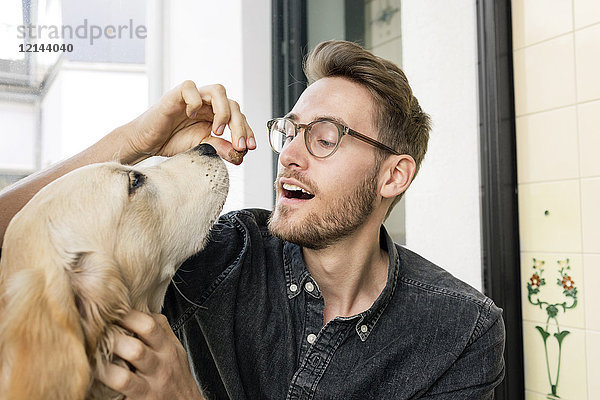 Junger Mann füttert Hund am Fenster