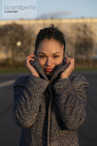 Porträt einer lächelnden jungen Frau in einem Mantel im Freien