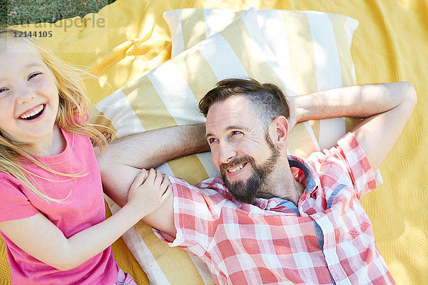 Glückliches Mädchen mit Vater auf einer Decke liegend