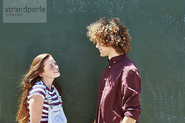 Lächelndes junges Paar vor einer grünen Wand