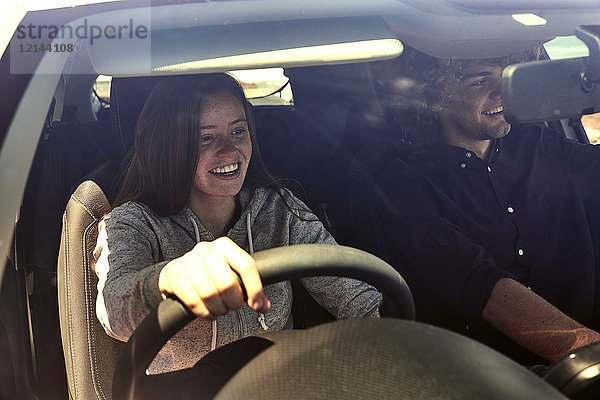 Glückliche junge Frau mit Freund beim Autofahren