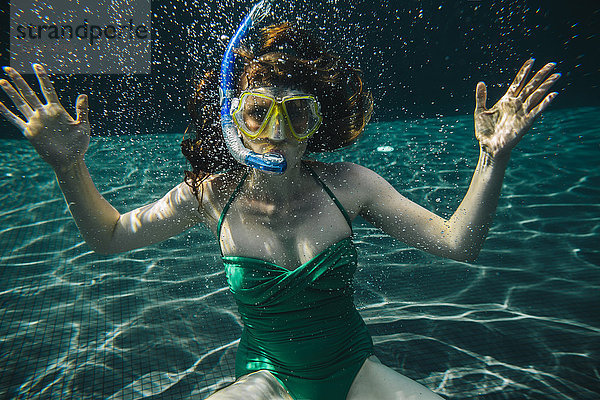 Porträt einer Frau mit Taucherbrille und Schnorchel unter Wasser im Schwimmbad