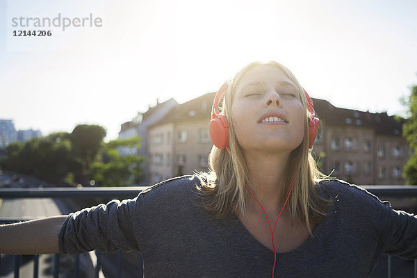 Portrait einer jungen Frau mit geschlossenen Augen Musik hören mit Kopfhörer