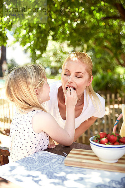 Mädchenfütterung Mutter mit Erdbeeren