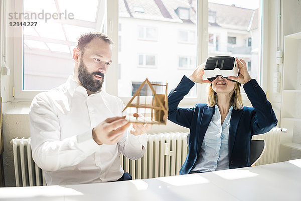 Frau und Mann mit Hausmodell und VR-Brille im Büro