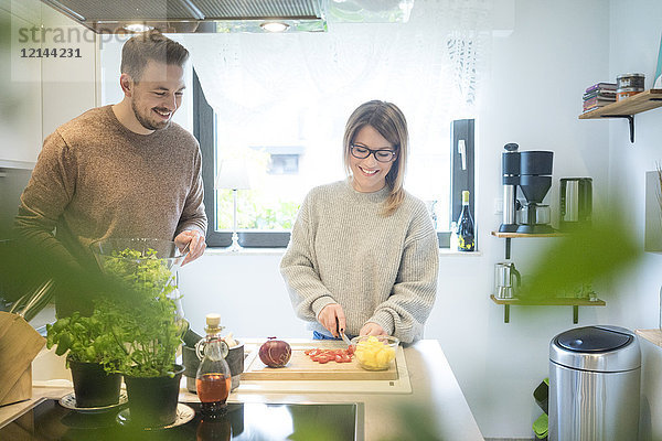 Ein glückliches Paar bereitet gemeinsam Salat in der Küche zu.