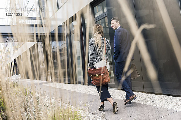 Geschäftsmann und Frau  die vor dem Bürogebäude spazieren gehen