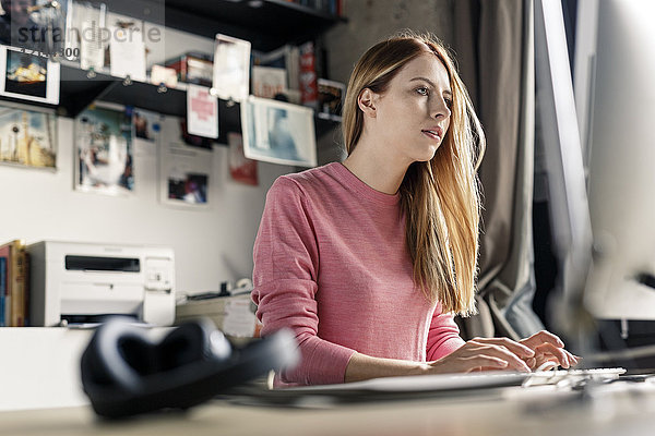 Junge Frau  die zu Hause am Schreibtisch am Computer arbeitet