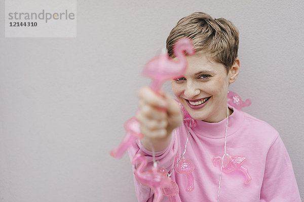 Porträt einer glücklichen Frau mit rosa Flamingolampen