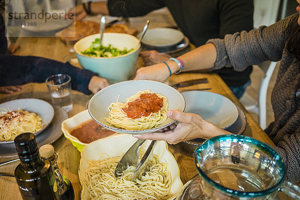 Familie am Tisch sitzend mit Spaghetti und Tomatensauce