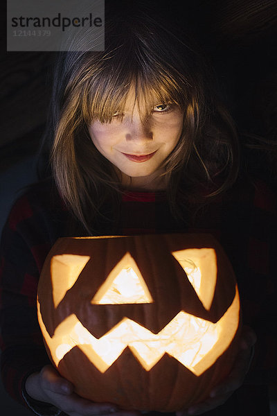 Porträt eines lächelnden Mädchens mit beleuchteten Jack O'Lantern an Halloween