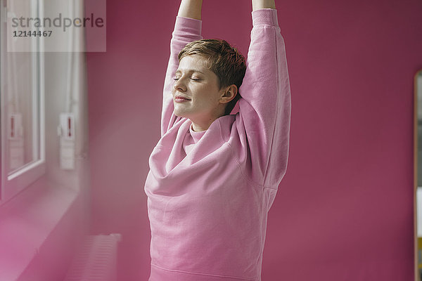 Frau in rosa Stretching am Fenster