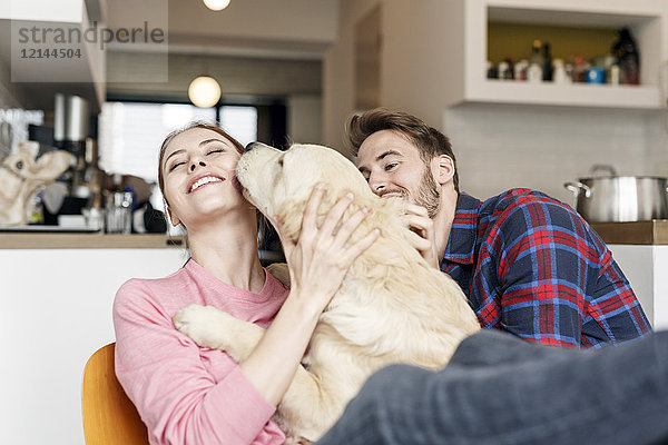 Glückliches junges Paar kuschelt mit Hund zu Hause