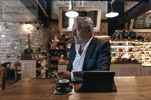 Senior Geschäftsmann sitzend im Cafe  mit digitalem Tablett  Tagträumen