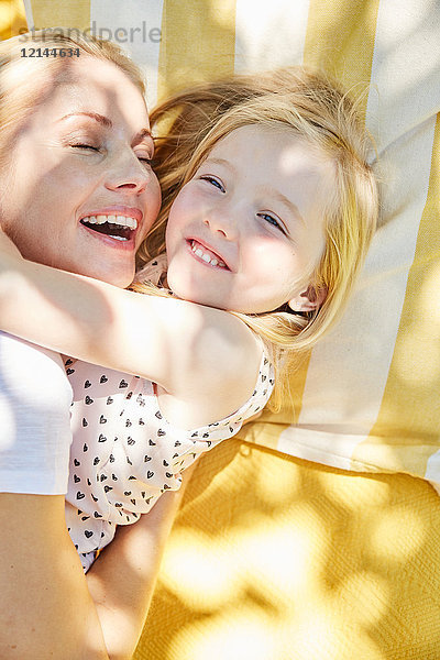 Fröhliches Mädchen und Mutter umarmend auf einer Decke